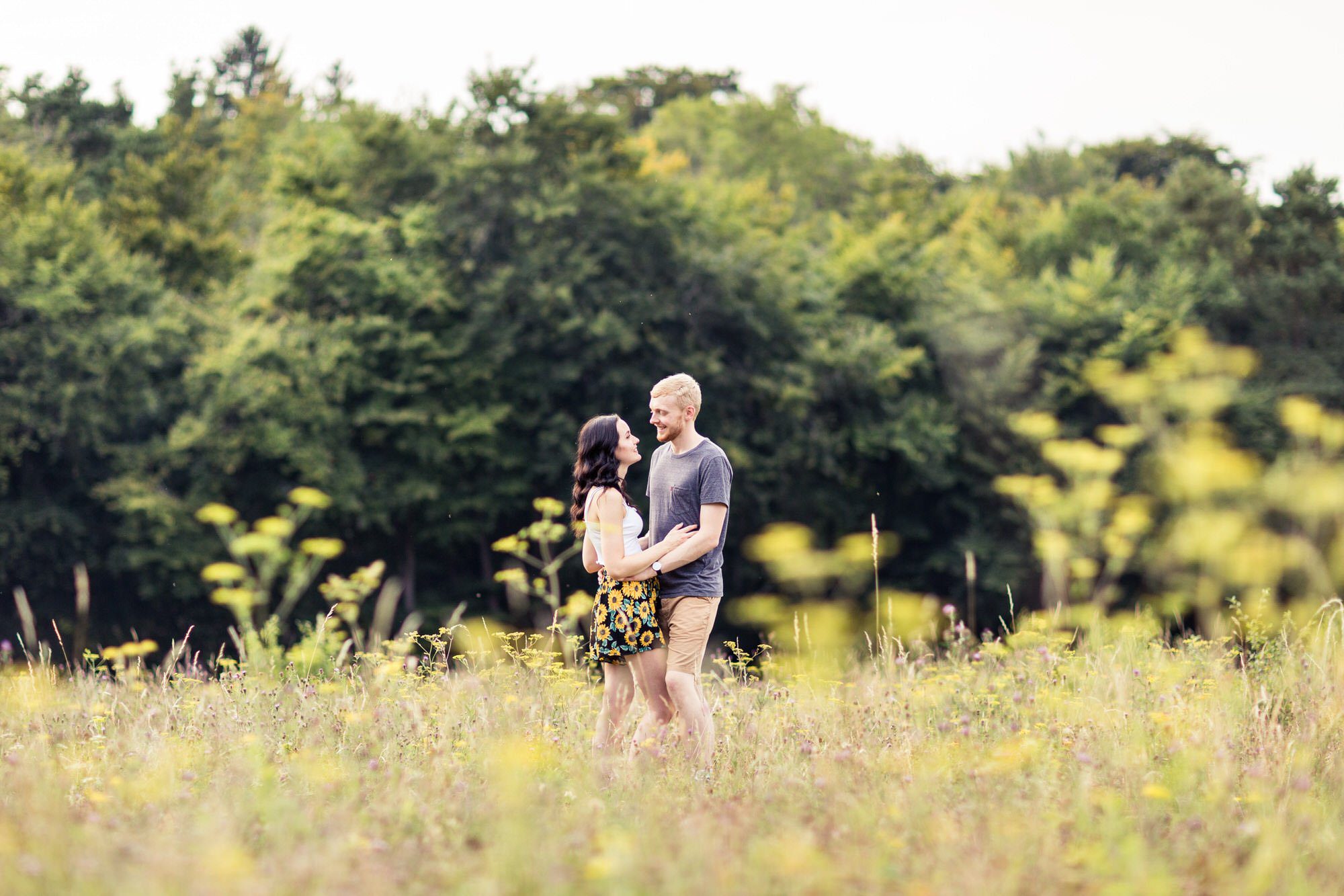 Engagement Photo Shoot - couple stand in wildflower meadow together.