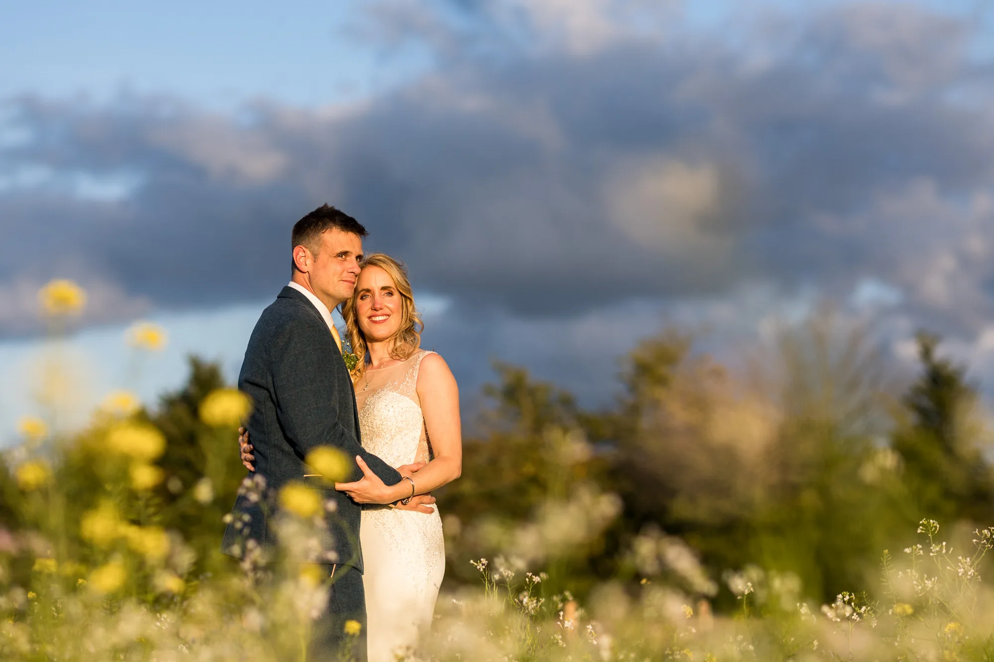 Professional Wedding Photography - bride and groom enjoy a sunset against a backdrop of a flowery meadow in West Sussex.