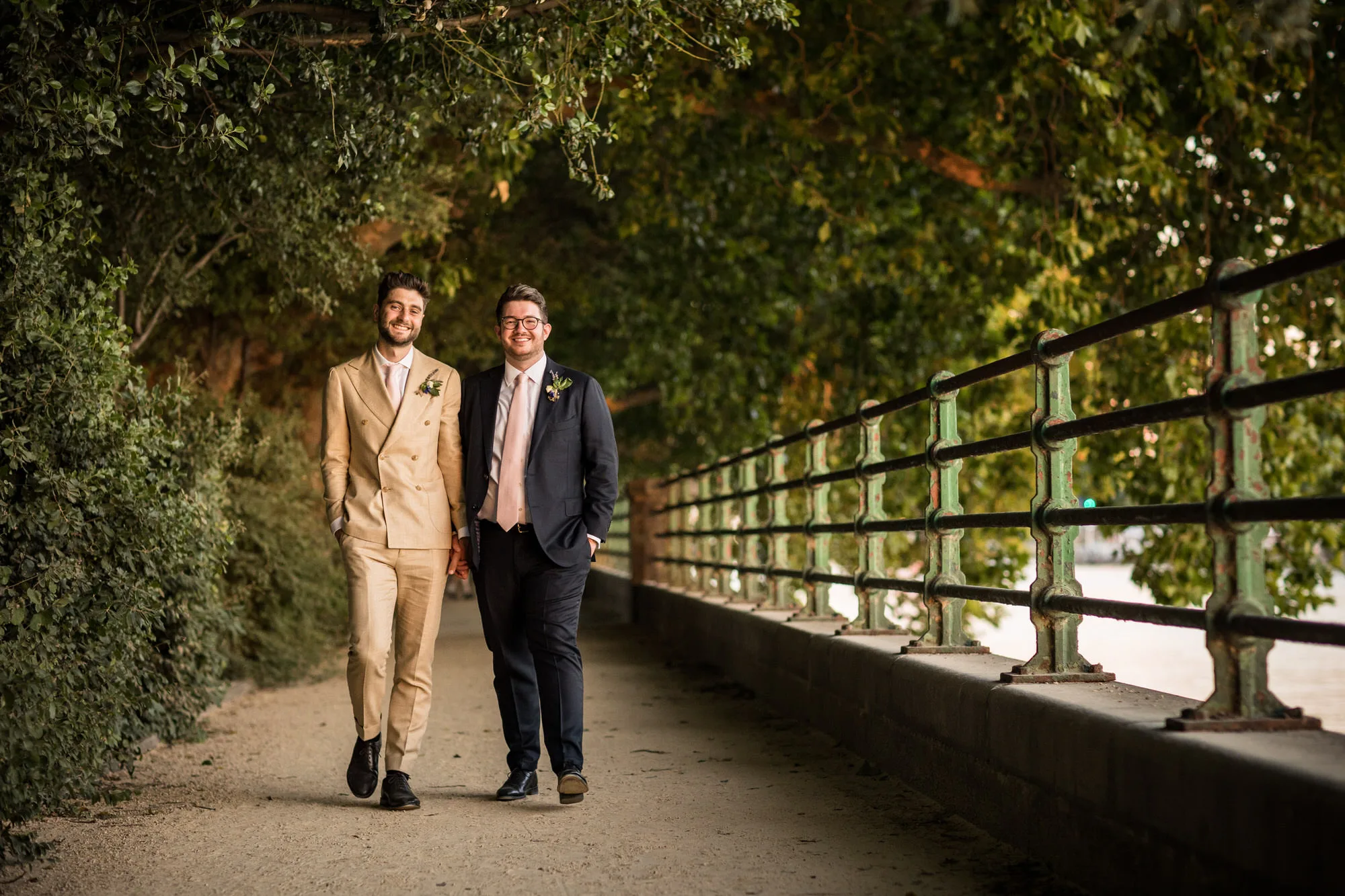 Questions to ask your wedding photographer - two men enjoy walking along the river in London on their wedding day.