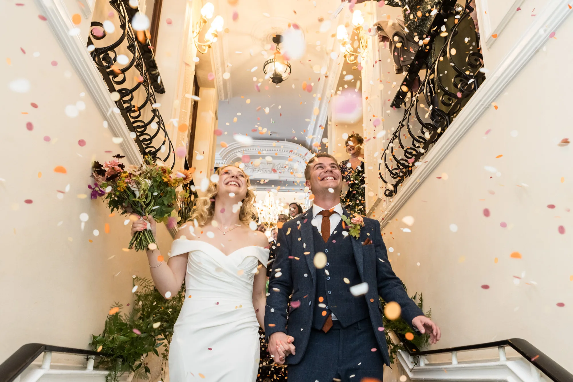 London wedding photographer - a couple exit their wedding venue being covered in confetti