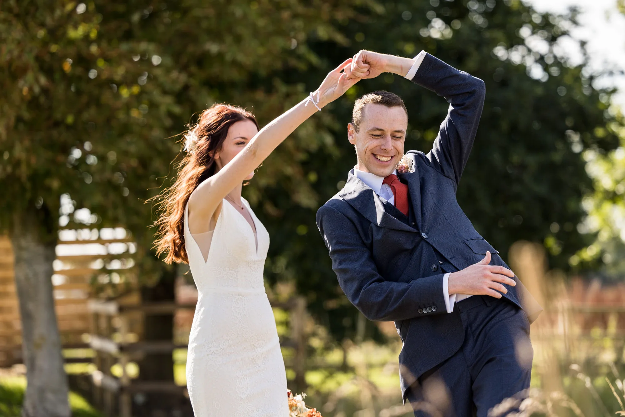 Hertfordshire wedding photographer - a man twirls in a dancefloor underneath his brides arm as they practised the first dance in the Hertfordshire countryside