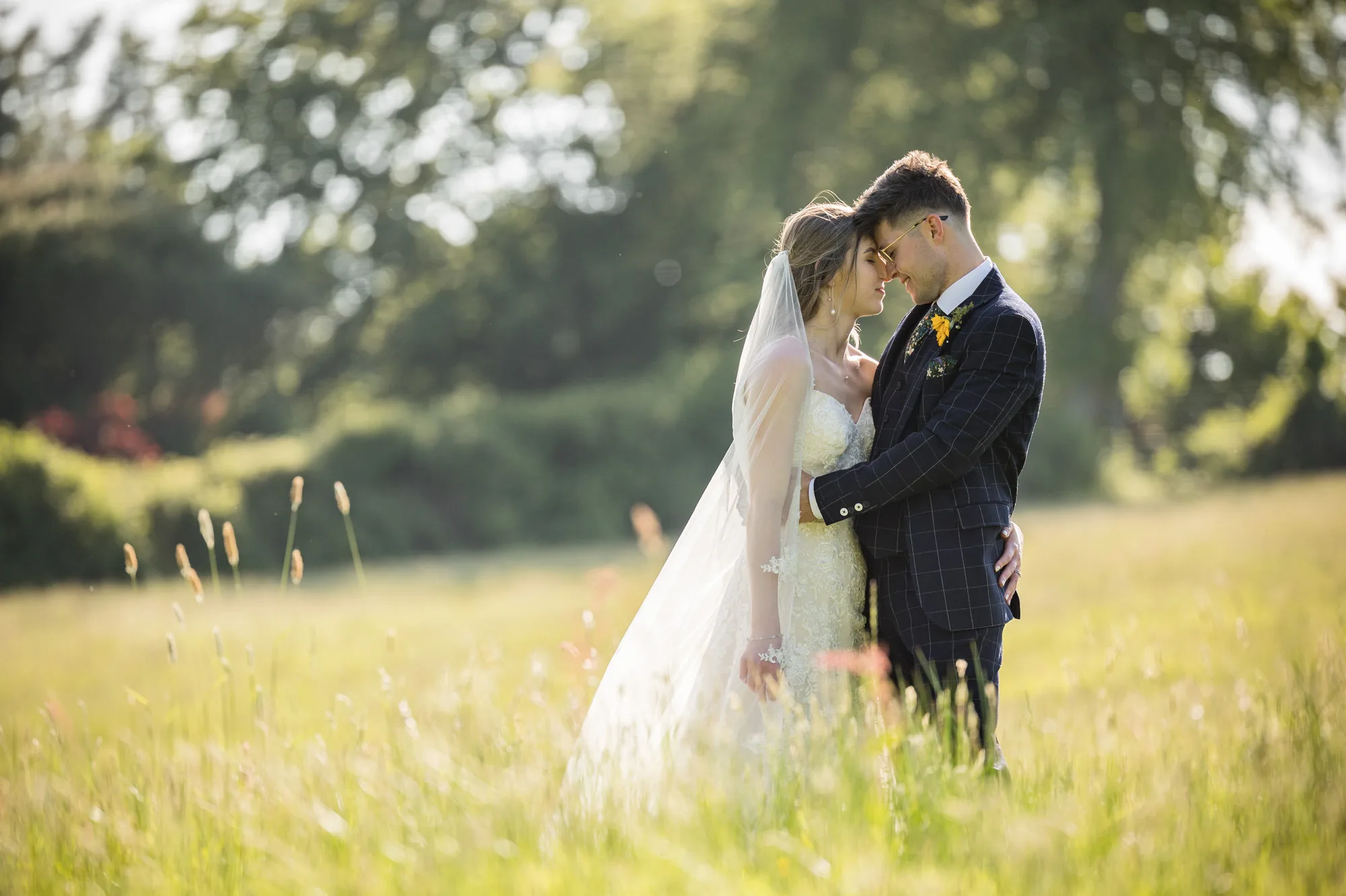 Reportage Wedding Photographer - a couple share a warm embrace in a meadow in East Sussex 