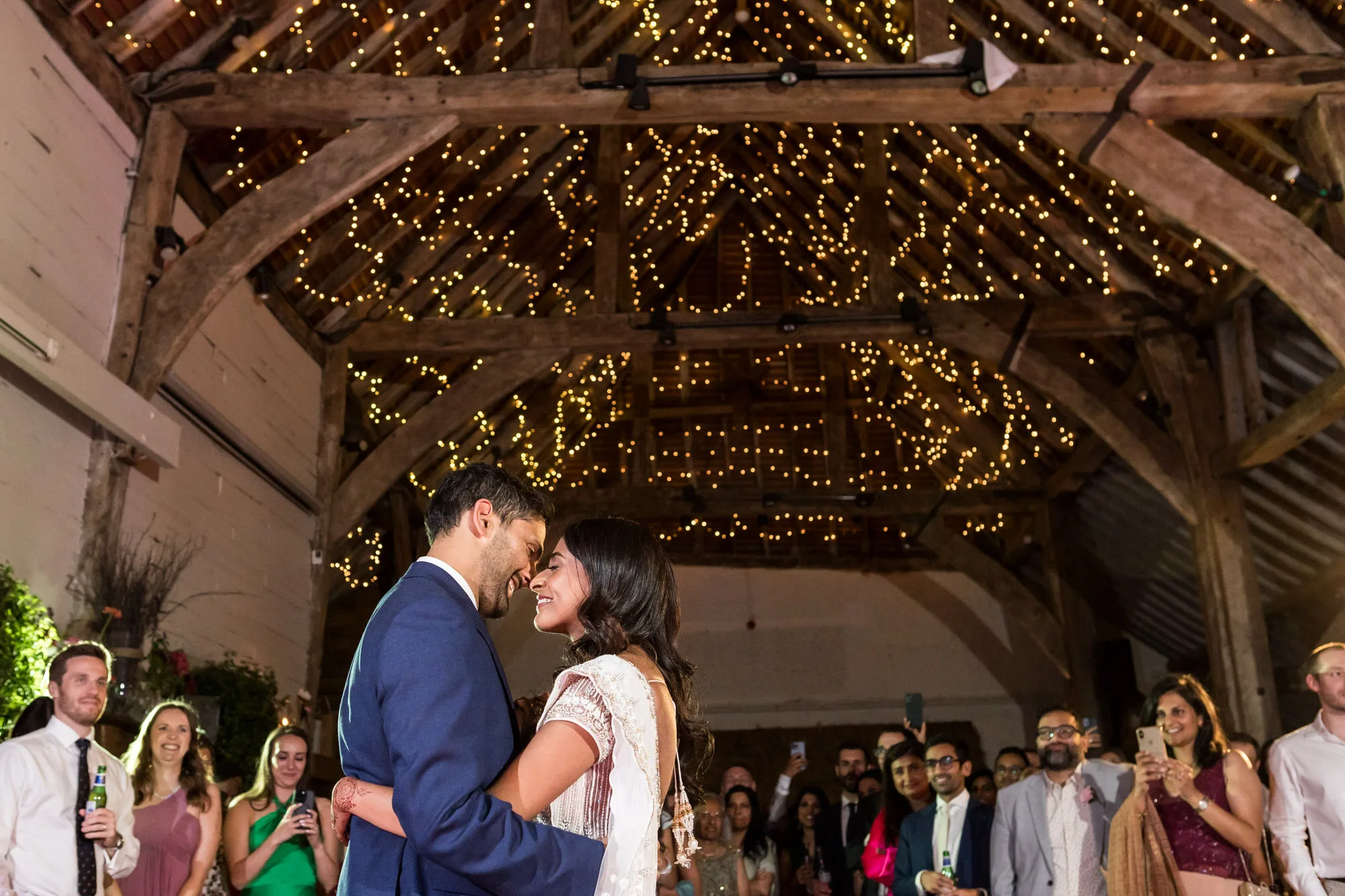 Reportage Wedding Photographer - a couple dance under a canopy of fairy lights at a barn wedding 