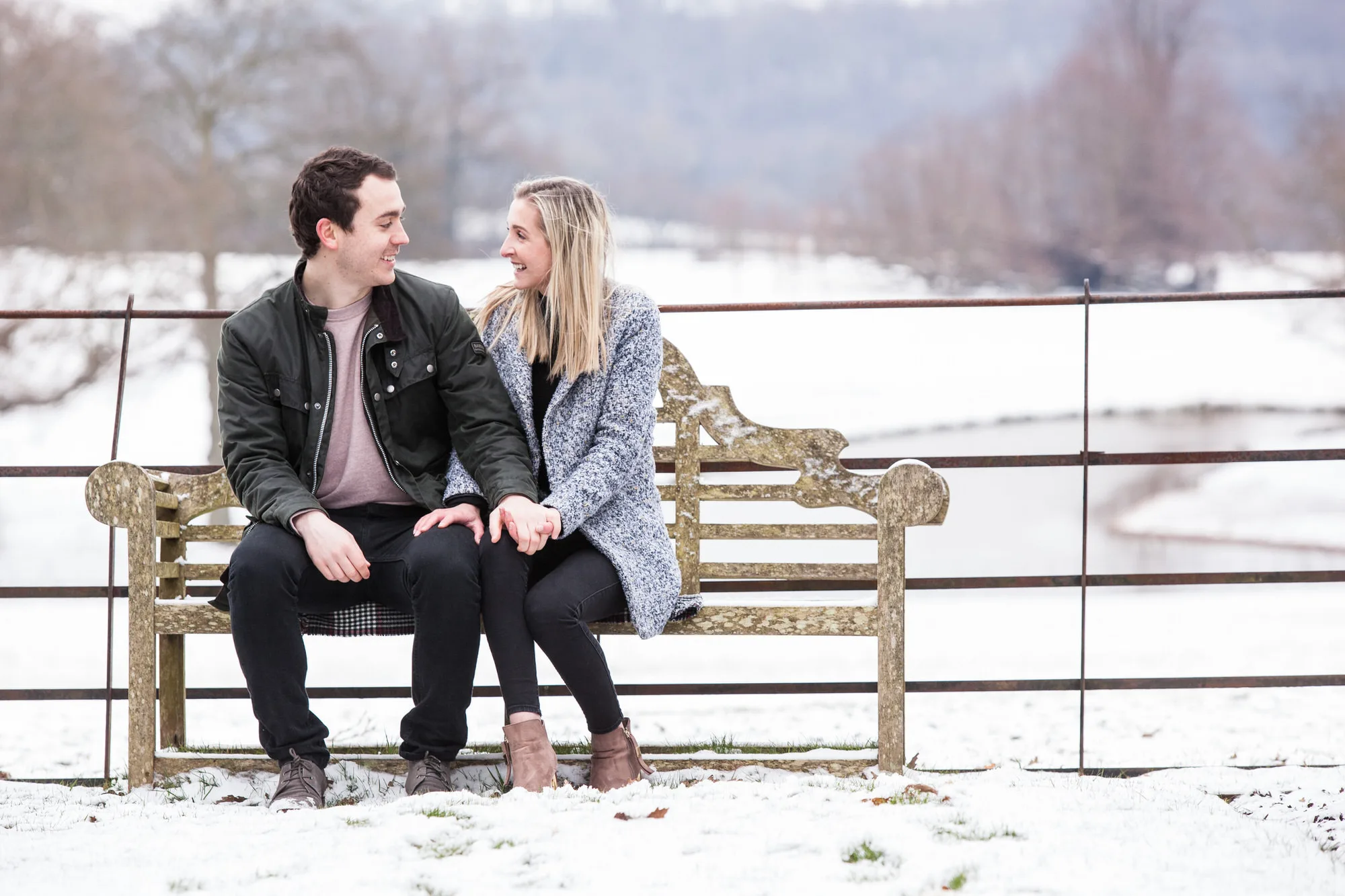 Engagement Photo Shoot - couple sitting together on a bench in the snow in the countryside of East Sussex