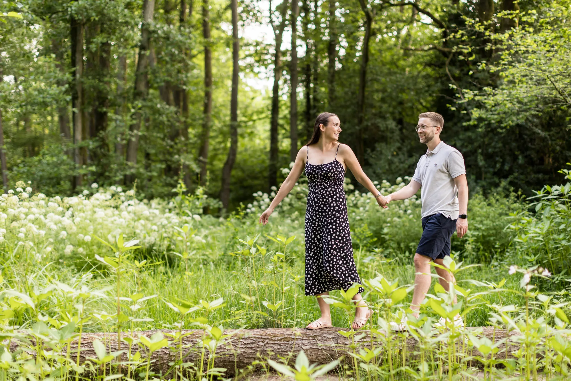 Reportage Wedding Photographer - a couple walk together through woodland on their engagement photo shoot 