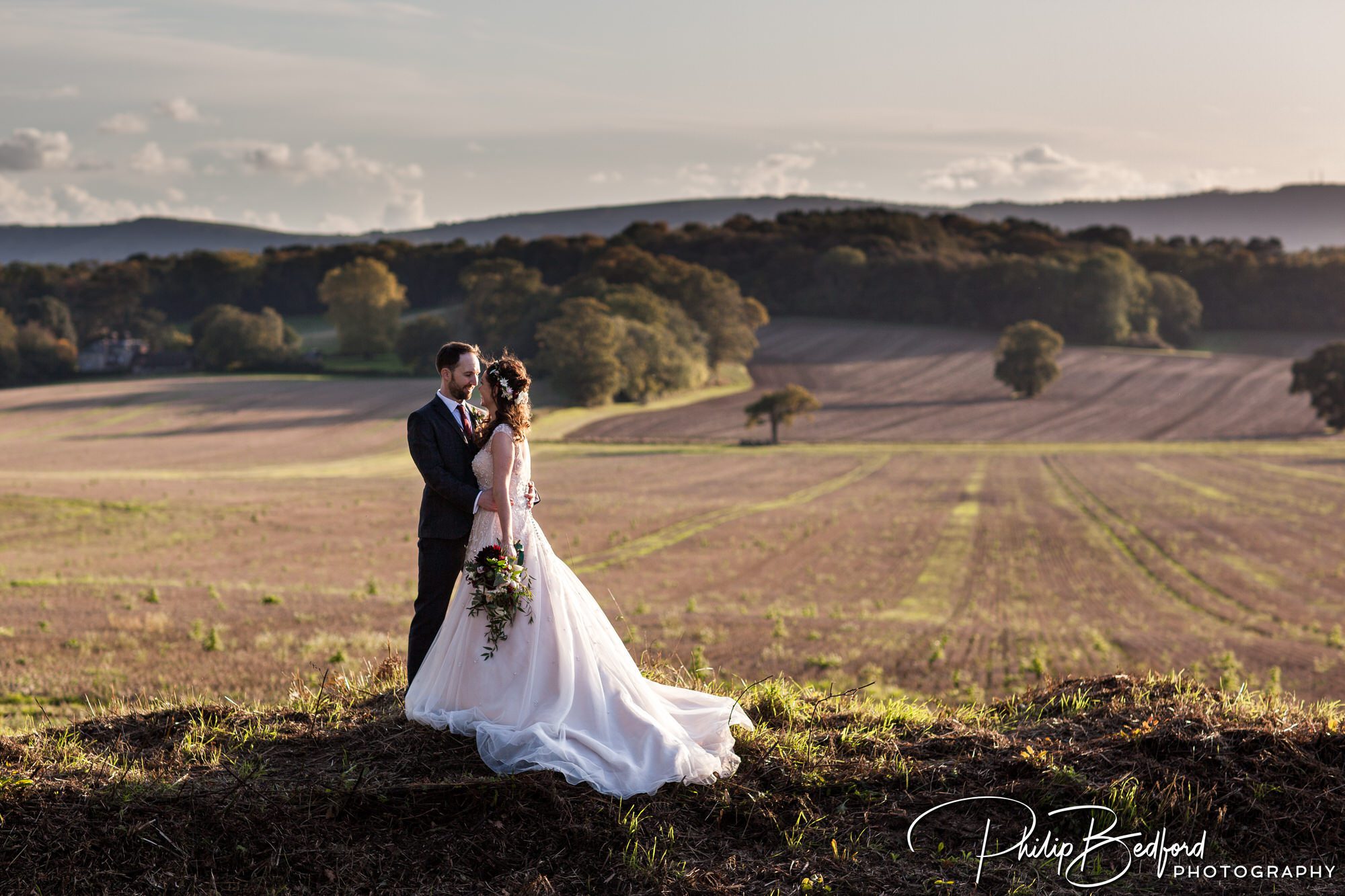 Fitzleroi Barn wedding photographer - bride and groom in golden hour, lighting with the South Downs countryside in the background 