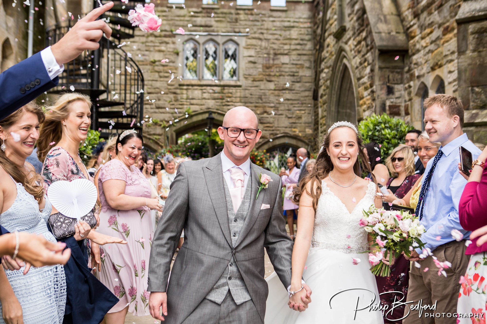 Relaxed Wedding Photograph of Bride & Groom Walking through hotel Grounds throwing Confetti