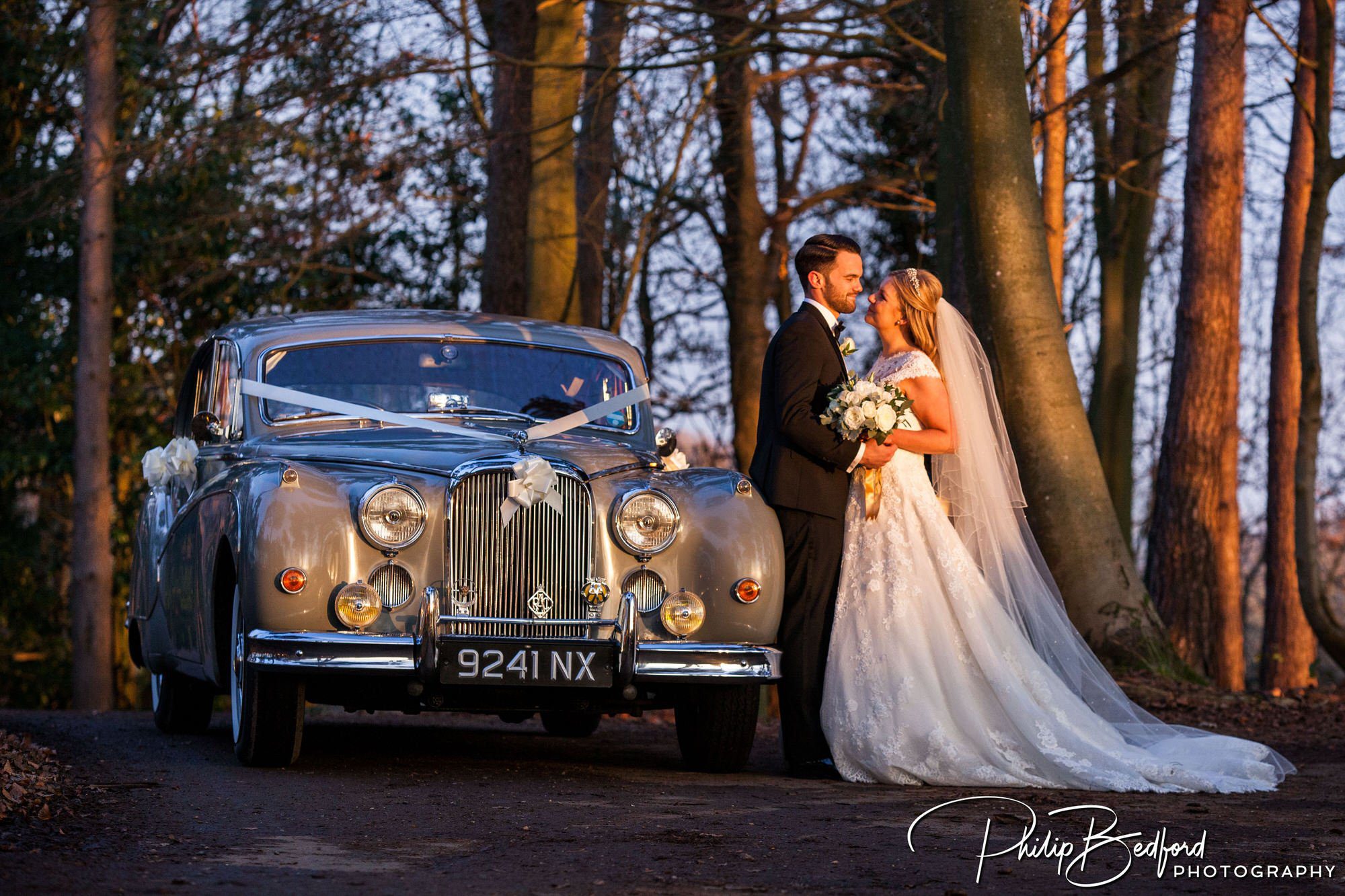 documentary style wedding photograph - bride and groom at sunset by their wedding car in Westerham Golf Club Wedding Westerham Kent