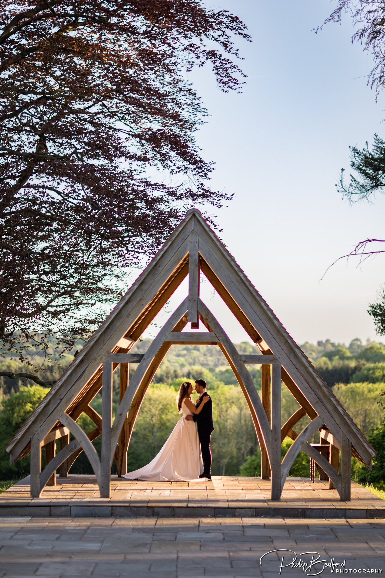 Bride and Groom under an arched gazebo at sunset